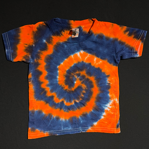 Orange & navy blue spiral toddler sized tie dye tee; laid flat on a solid black background.