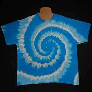 Front side of an aqua & electric blue, with white, spiral tie dye t-shirt design; laid flat on a solid black background