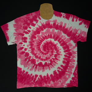 An example of a finished, hand-dyed when ordered, one-of-a-kind, bubblegum pink & white spiral short sleeve tie dye shirt design; laid flat on a solid black background