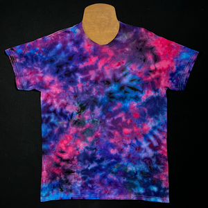 Front side of a finished, one-of-a-kind blue, pink & purple marbled ice tie-dyed short sleeve shirt design; laid flat on a solid black background before shipping