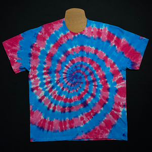 An example of a finished blue & pink cotton candy spiral short sleeve tie dye shirt design; laid flat on a solid black background