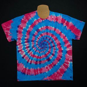 An example of a finished blue & pink cotton candy spiral short sleeve tie dye shirt design; laid flat on a solid black background 