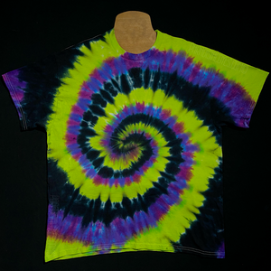 A black, neon lime green & blue violet spiral tie dye short sleeve shirt, laid flat on a solid black background