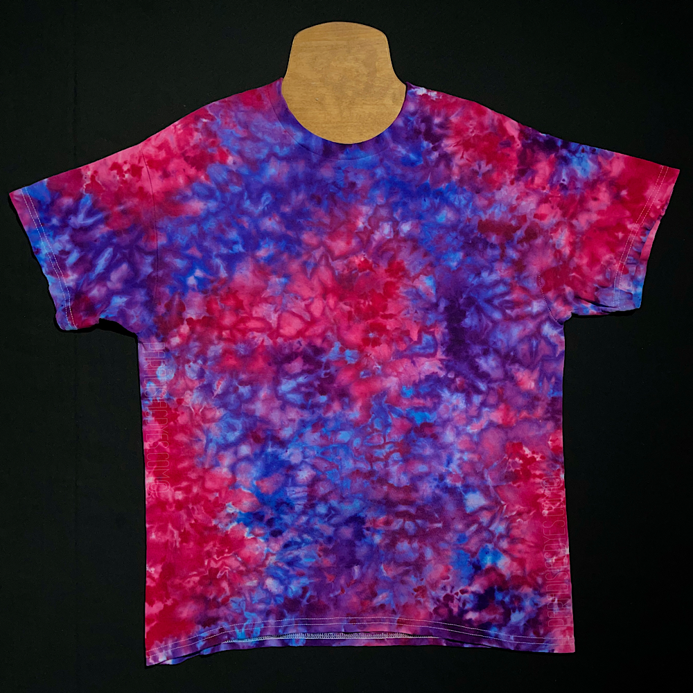 An example of a pink & purple ice dyed splatter pattern short sleeve t-shirt; laid flat on a solid black background