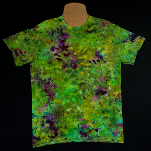 Front side of a finished, one-of-a-kind, weed bud inspired green & purple marbled ice tie-dyed short sleeve shirt design; laid flat on a solid black background 