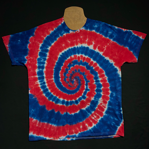 An example of another, different, finished red, white & blue spiral tie dye short sleeve shirt; laid flat on a solid black background