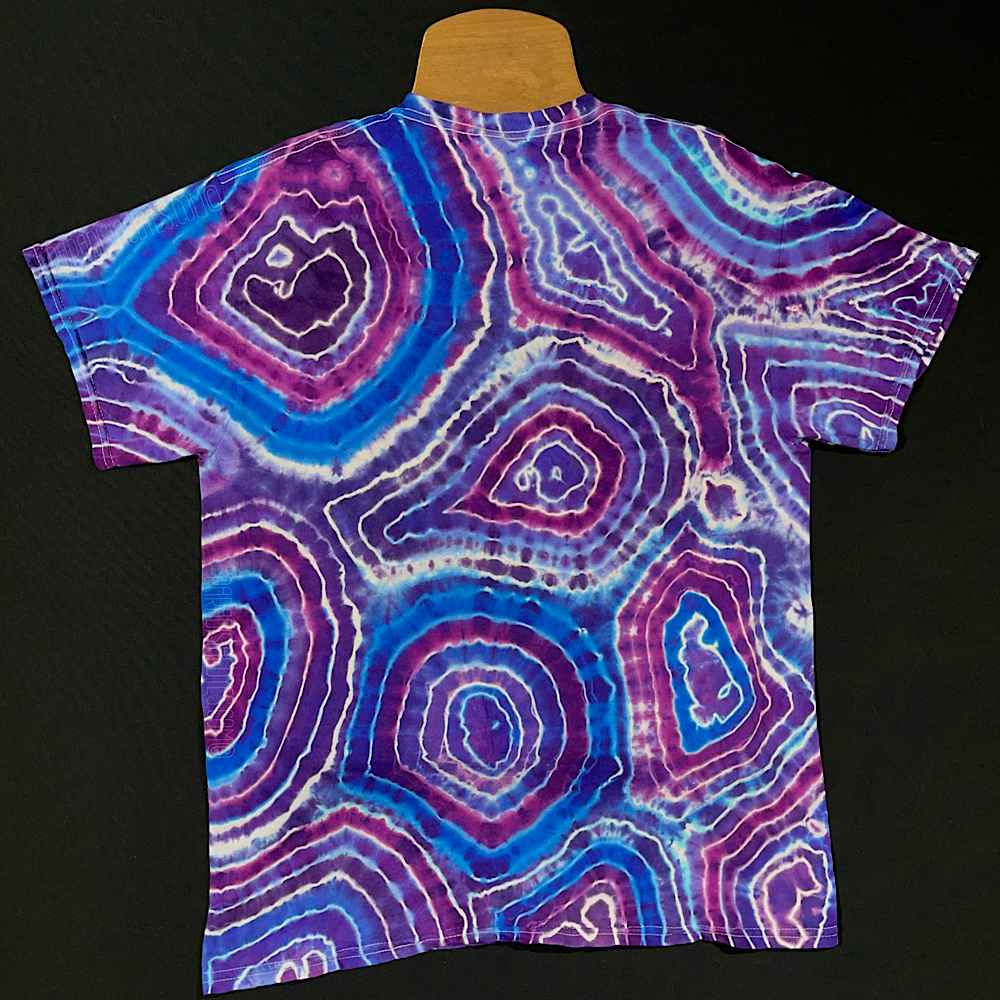 Front side of a handmade-to-order purple amethyst quartz geode pattern tie dye short sleeve tee; laid flat on a solid black background 