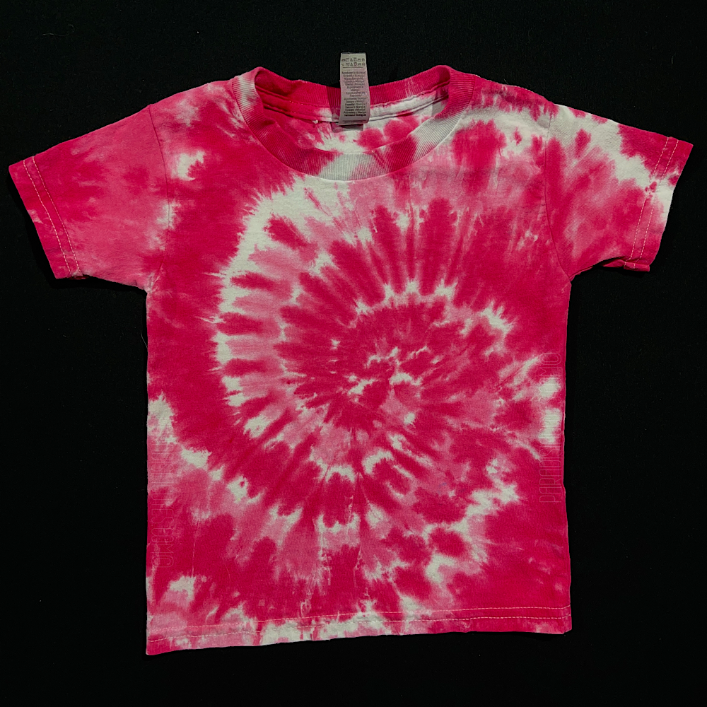An example of a finished, one-of-a-kind, hand-dyed when ordered toddler sized tie dye shirt design, featuring bright bubblegum pink & white in a classic spiral design; laid flat on a solid black background 