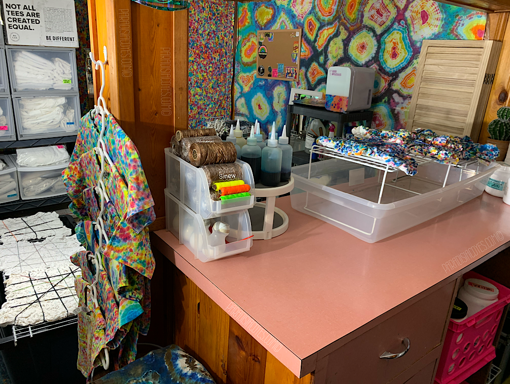 Photo depicting the finished result of the stain-proofed tie dye art studio, with a rainbow splatter tapestry on the wall and a multi-colored area rug