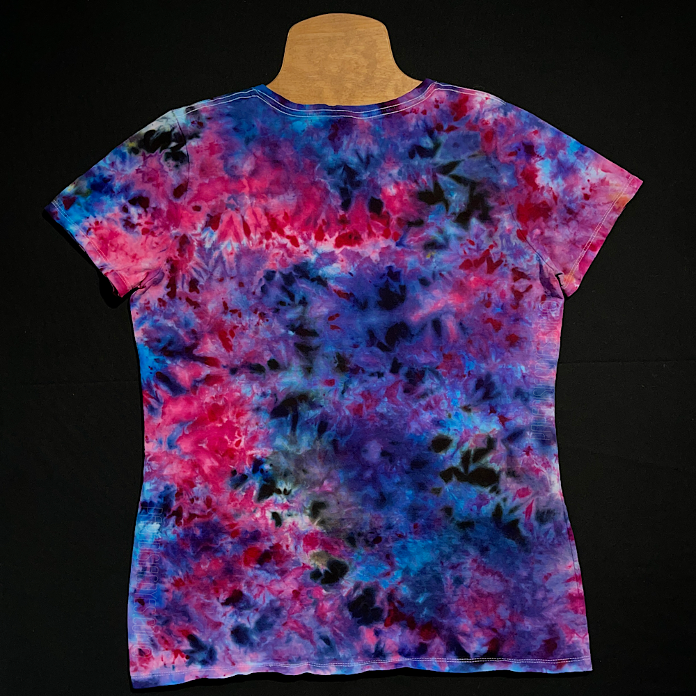 Back side of a ladies' v-neck style tie dye shirt in the blue, pink & purple cloud 9 marbled ice dye design; laid flat on a solid black background