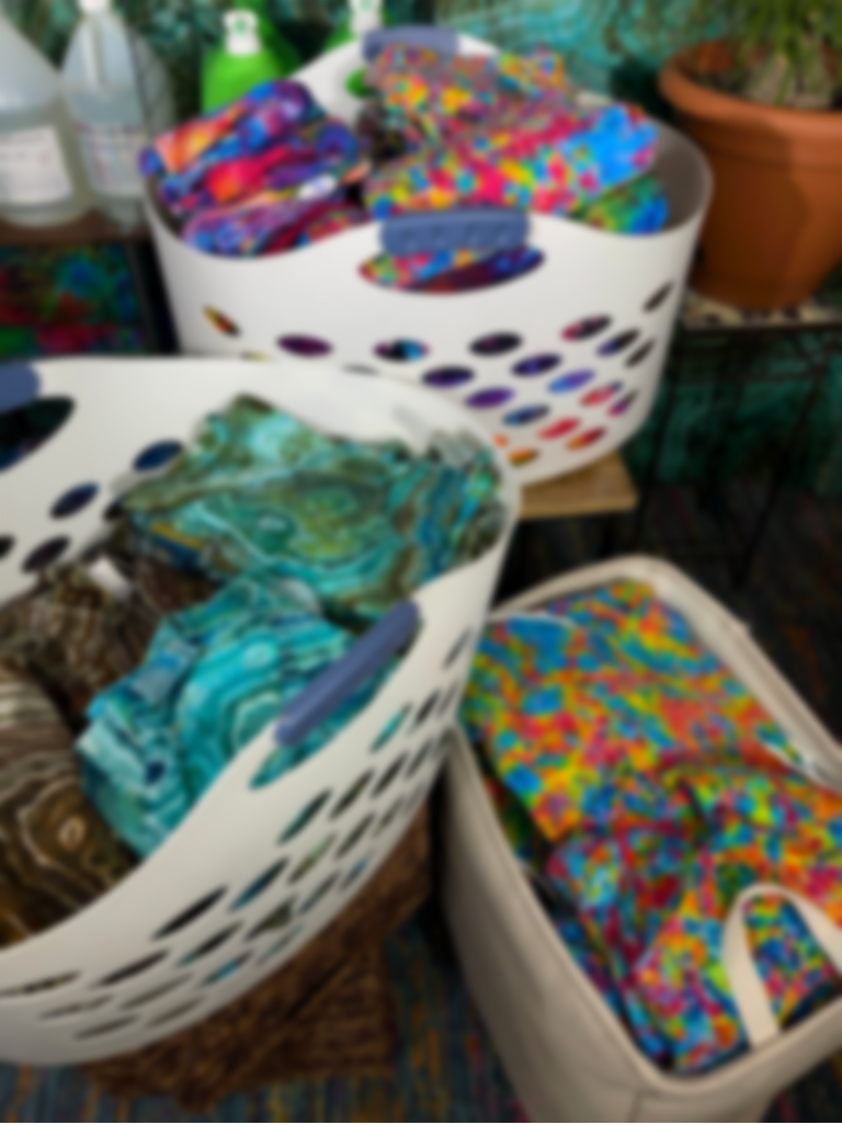 Three laundry baskets, each full of folded, finished tie-dyes