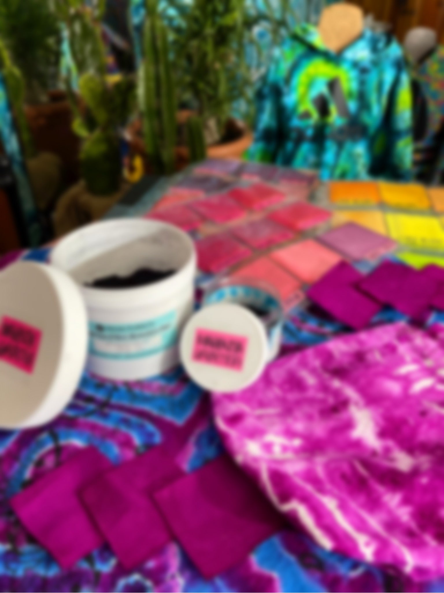 Slightly blurred image featuring Magenta Galactica dye powder as well as tie dye and ice dyed fabric sample swatches of the new fiber reactive dye color