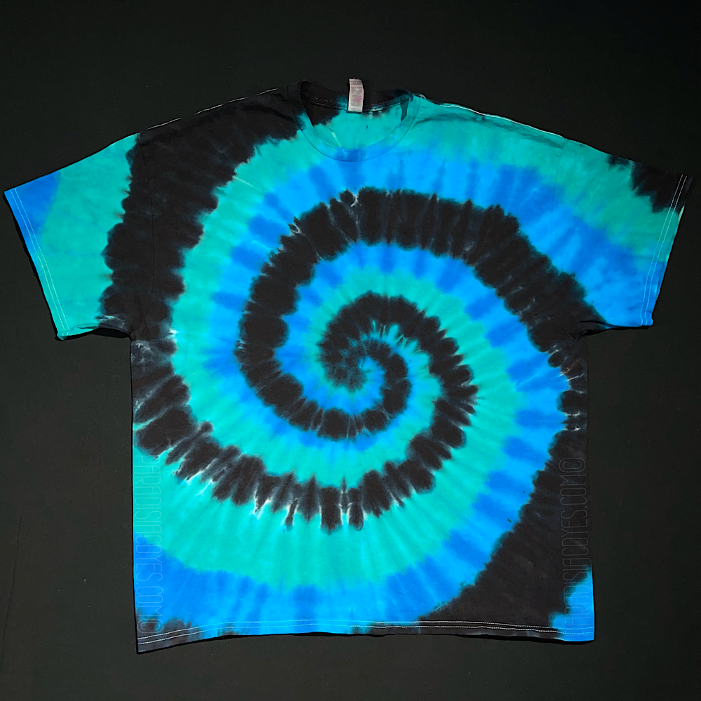 A different black, blue & teal spiral tie dye short sleeve shirt; also laid flat on a solid black background.