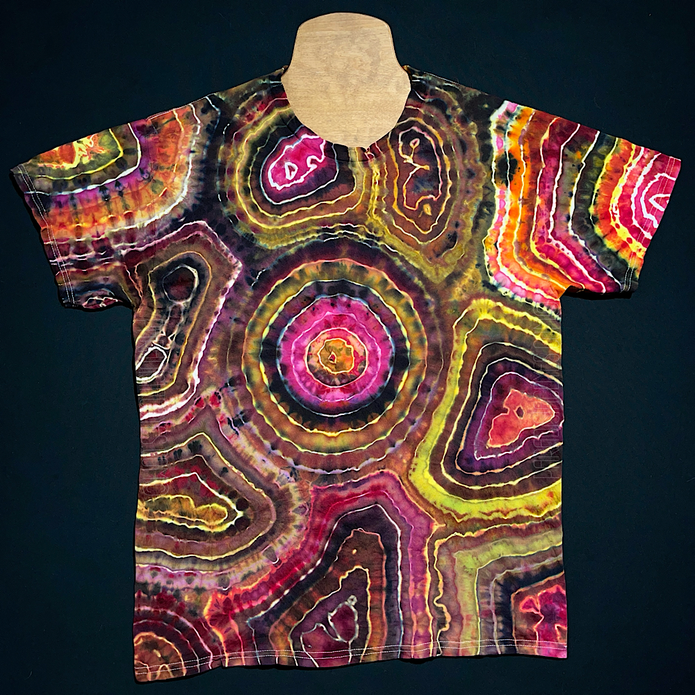 Front side of a short sleeve, crewneck style t-shirt featuring an agate geode reminiscent pattern with shades of pink, yellow & black