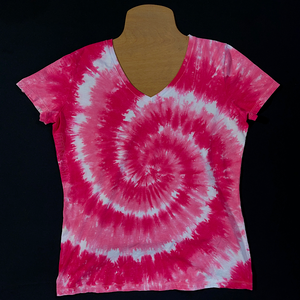 Front side of a women's v-neck style short sleeve t-shirt featuring a bubblegum pink & white spiral tie dye design; laid flat on a solid black background 