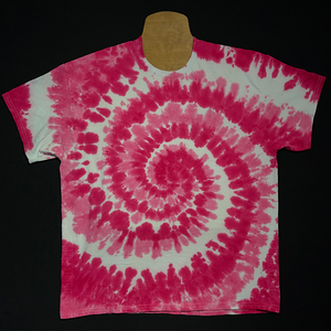 An example of a finished, hand-dyed when ordered, one-of-a-kind, bubblegum pink & white spiral short sleeve tie dye shirt design; laid flat on a solid black background 