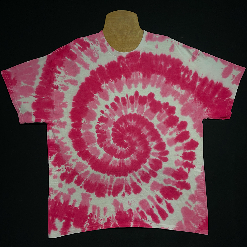 An example of a finished, hand-dyed when ordered, one-of-a-kind, bubblegum pink & white spiral short sleeve tie dye shirt design; laid flat on a solid black background 