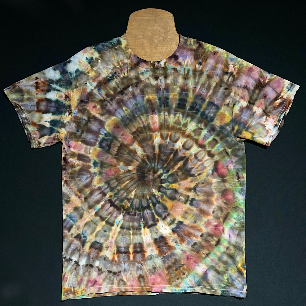 An example of another, different Earthy Ice Dye Spiral T-Shirt, featuring all neutral, brown & gray shades, with detailing reminiscent of a watercolor painting; laid flat on a solid black background