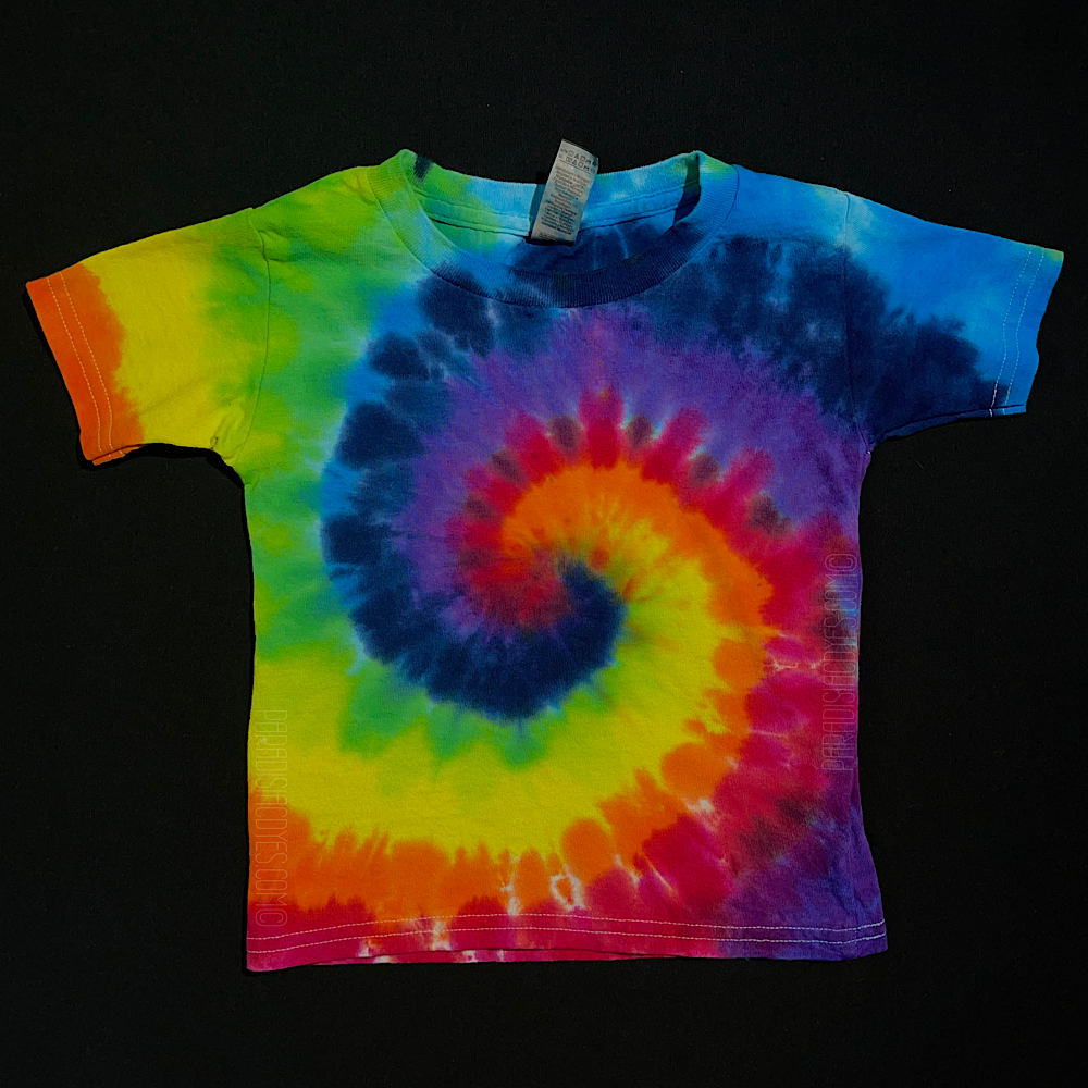 An example of another, different toddler sized ROYGBIV rainbow spiral short sleeve tie dye shirt design; laid flat on a solid black background 