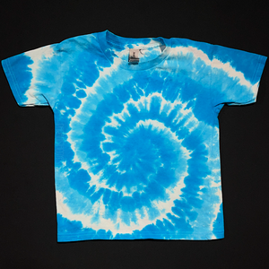 A duo-toned blue spiral tie dye toddler sized short sleeve shirt; laid flat on a solid black background 