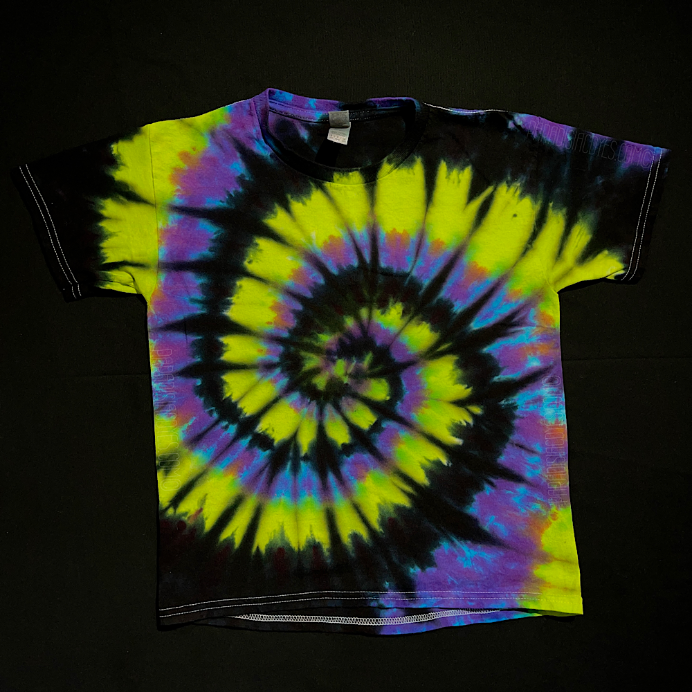 A toddler sized black, green & purple spiral short sleeve tie dye shirt; laid flat on a solid black background