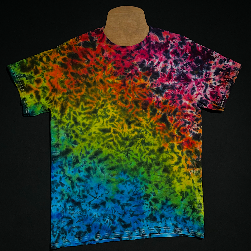 Front side of a pink, orange, yellow, green & blue ombre ice dyed t-shirt with intense black splatter pattern over top the rainbow gradient 