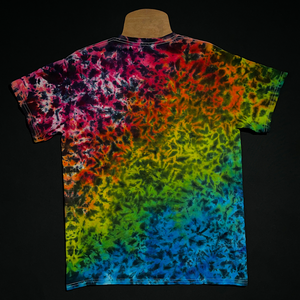 Back side of a Midnight Marbled Rainbow Ice Dye T-Shirt; laid flat on a solid black background