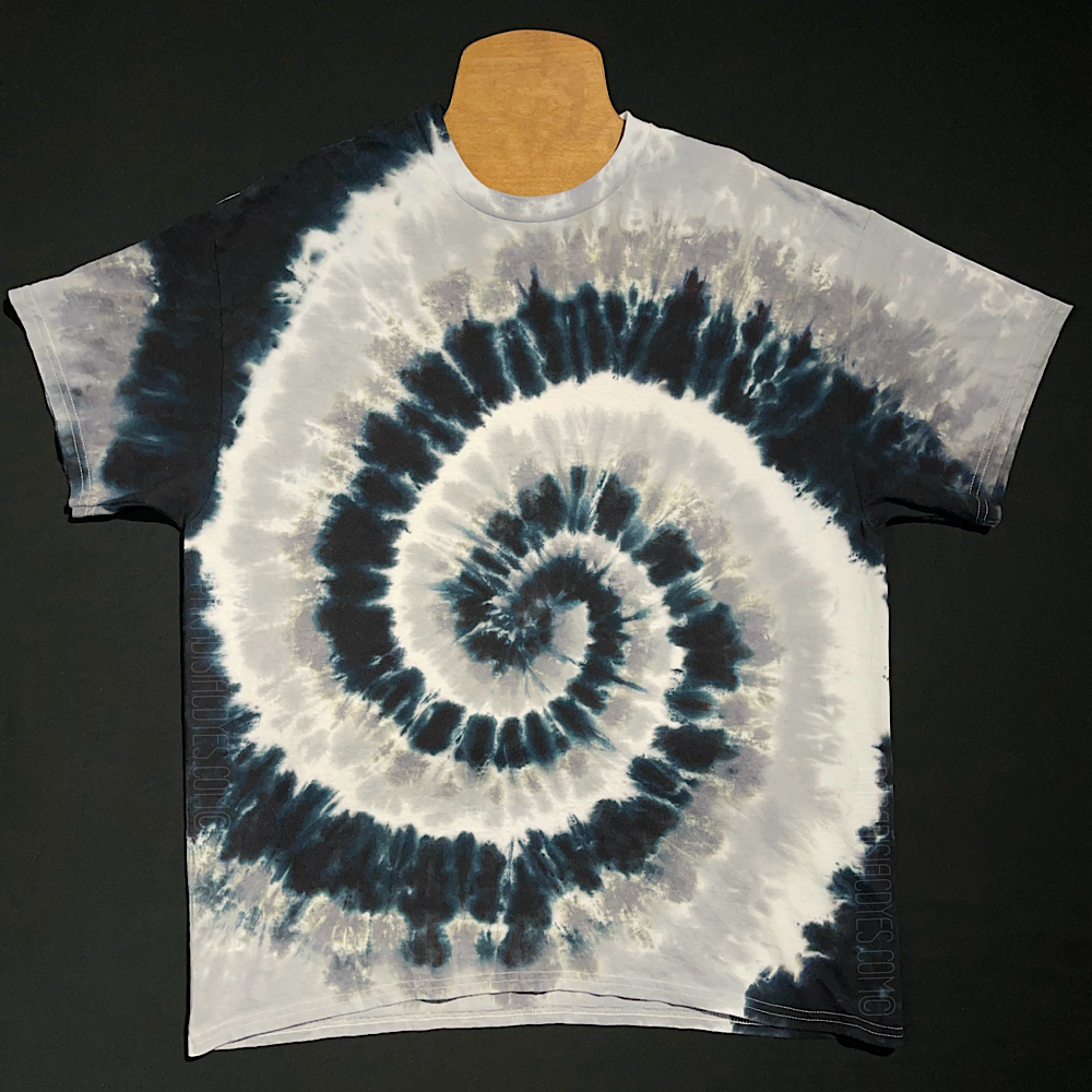 Another, different monochrome tie dye short sleeve shirt, featuring black, gray & white in a spiral design; laid flat on a solid black background