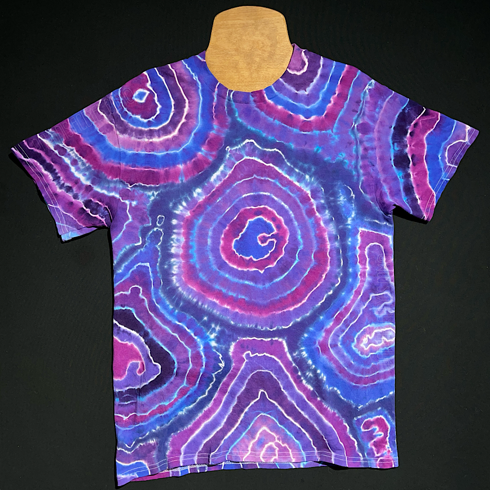 Front side of a hand-dyed, one-of-a-kind, geode pattern t-shirt featuring an array of differing purple shades, laid flat on a solid black background