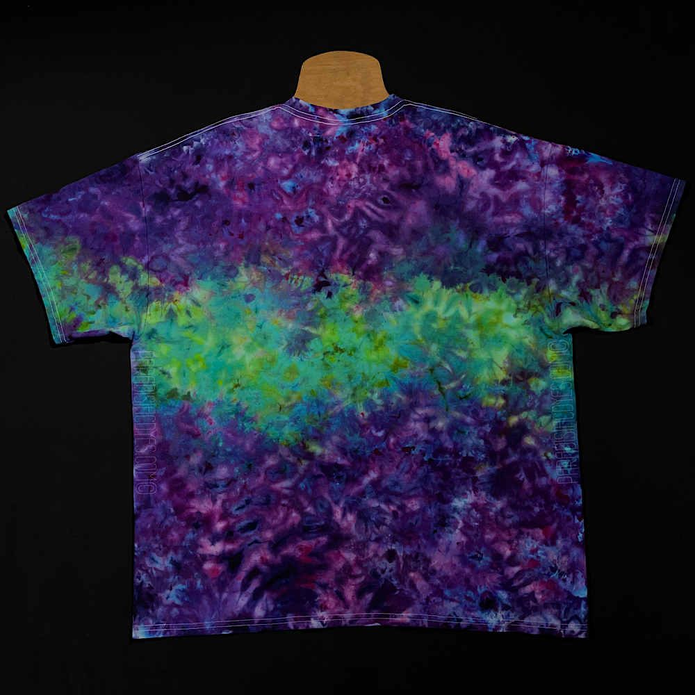 Back side of a finished, hand-dyed, one-of-a-kind, purple & mint green marbled splatter ice dye t-shirt design; laid flat on a solid black background 
