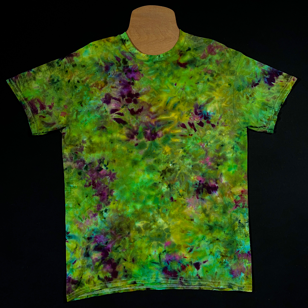 Front side of a finished, one-of-a-kind, weed bud inspired green & purple marbled ice tie-dyed short sleeve shirt design; laid flat on a solid black background 