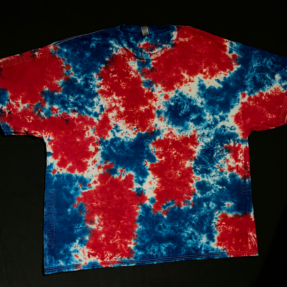 An example of another finished red, white & blue splatter pattern tie dye t-shirt; laid flat on a solid black background 