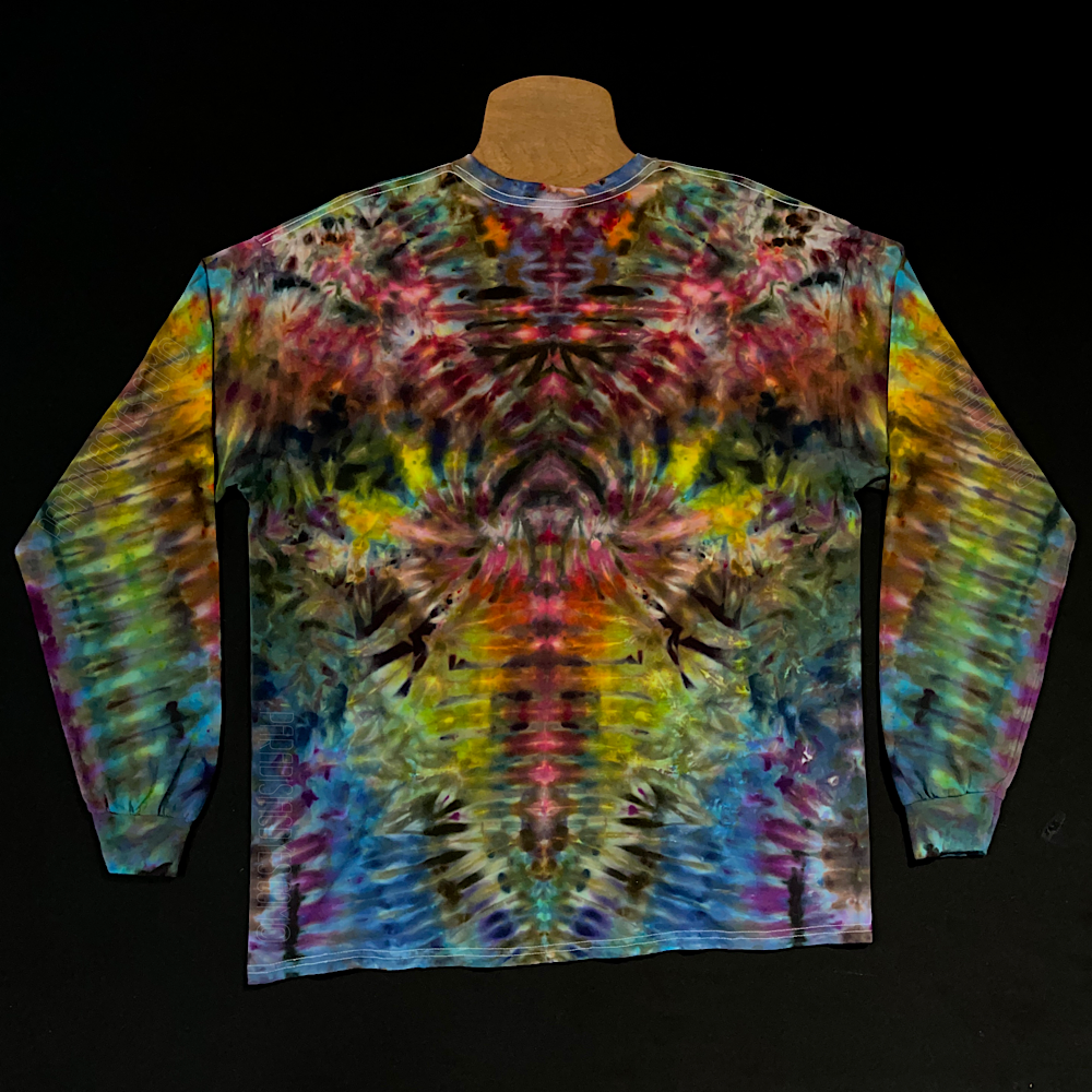 Back side of a rainbow colored long sleeve tie dye shirt featuring an abstract, symmetrical pattern; laid flat on a solid black background 