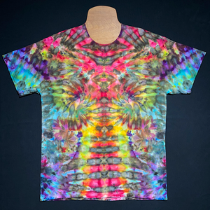 Front side of a one-of-a-kind, abstract, symmetrical rainbow ice tie-dyed t-shirt design; laid flat on a solid black background.