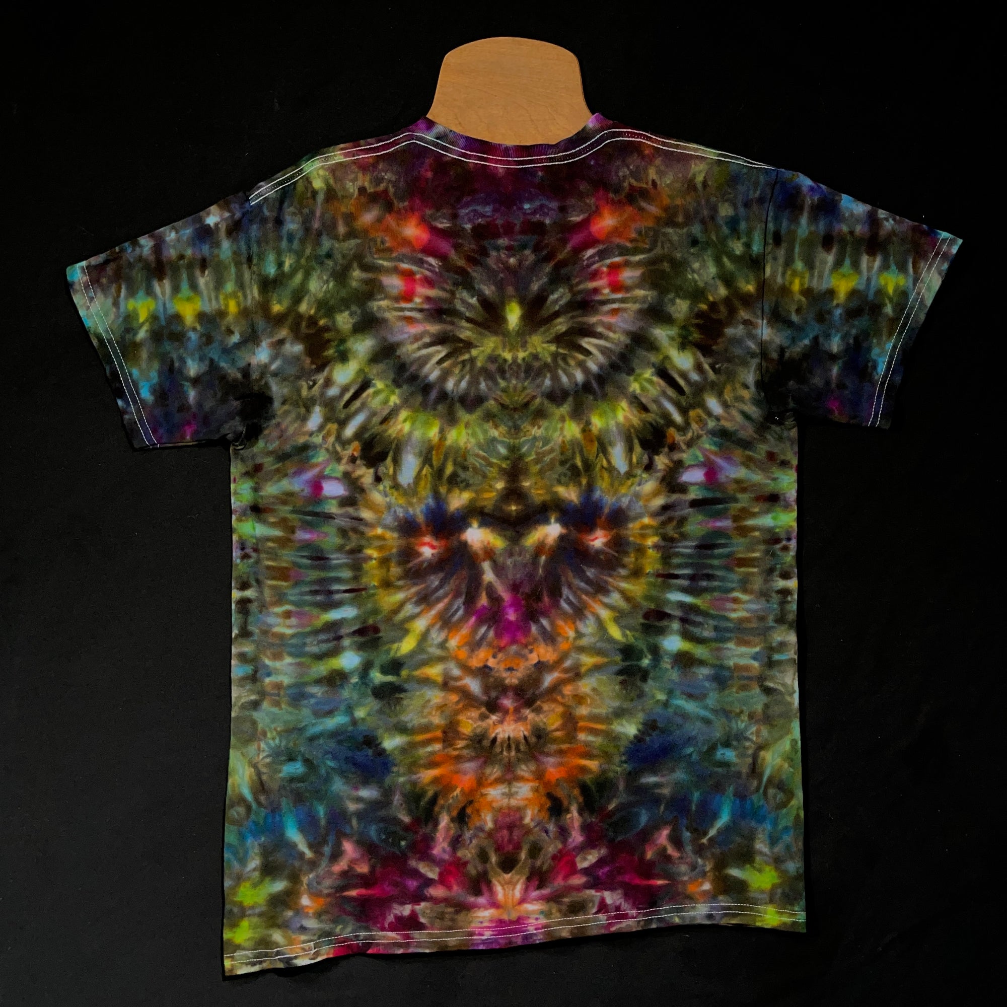 Front side of a multi-colored, dark, intense rainbow psychedelic mindscape ice tie-dyed t-shirt design; laid flat on a solid black background 