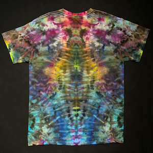 Back side of a hand-dyed, one-of-a-kind, abstract, symmetrical Psychedelic Mindscape ice tie-dyed design on a short sleeve, size adult medium tee that features dull, muddy rainbow colors; laid flat on a solid black background.