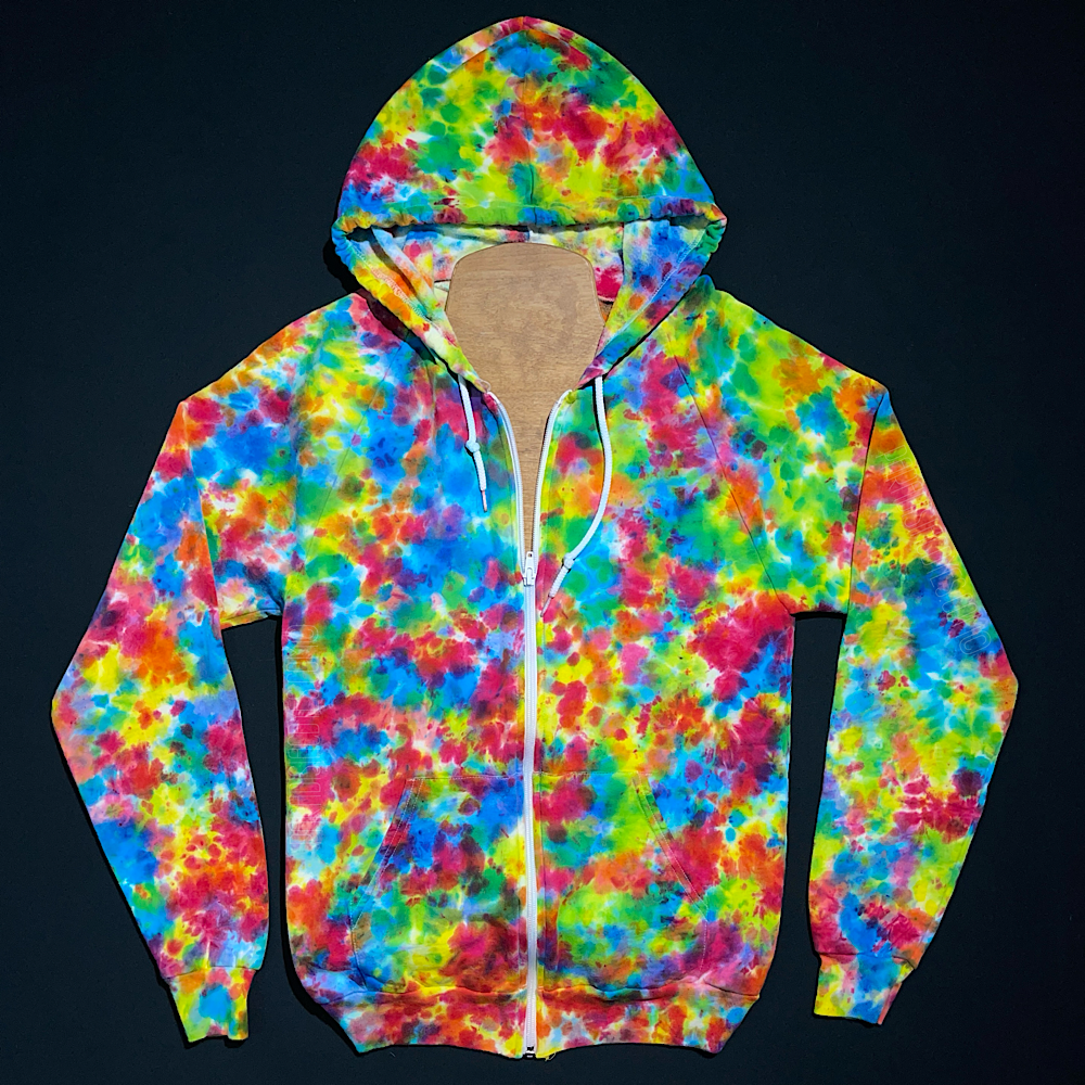 Front side of a zip-up hoodie featuring a hand-dyed, one-of-a-kind rainbow splatter pattern tie dye design, laid flat on a solid black background.
