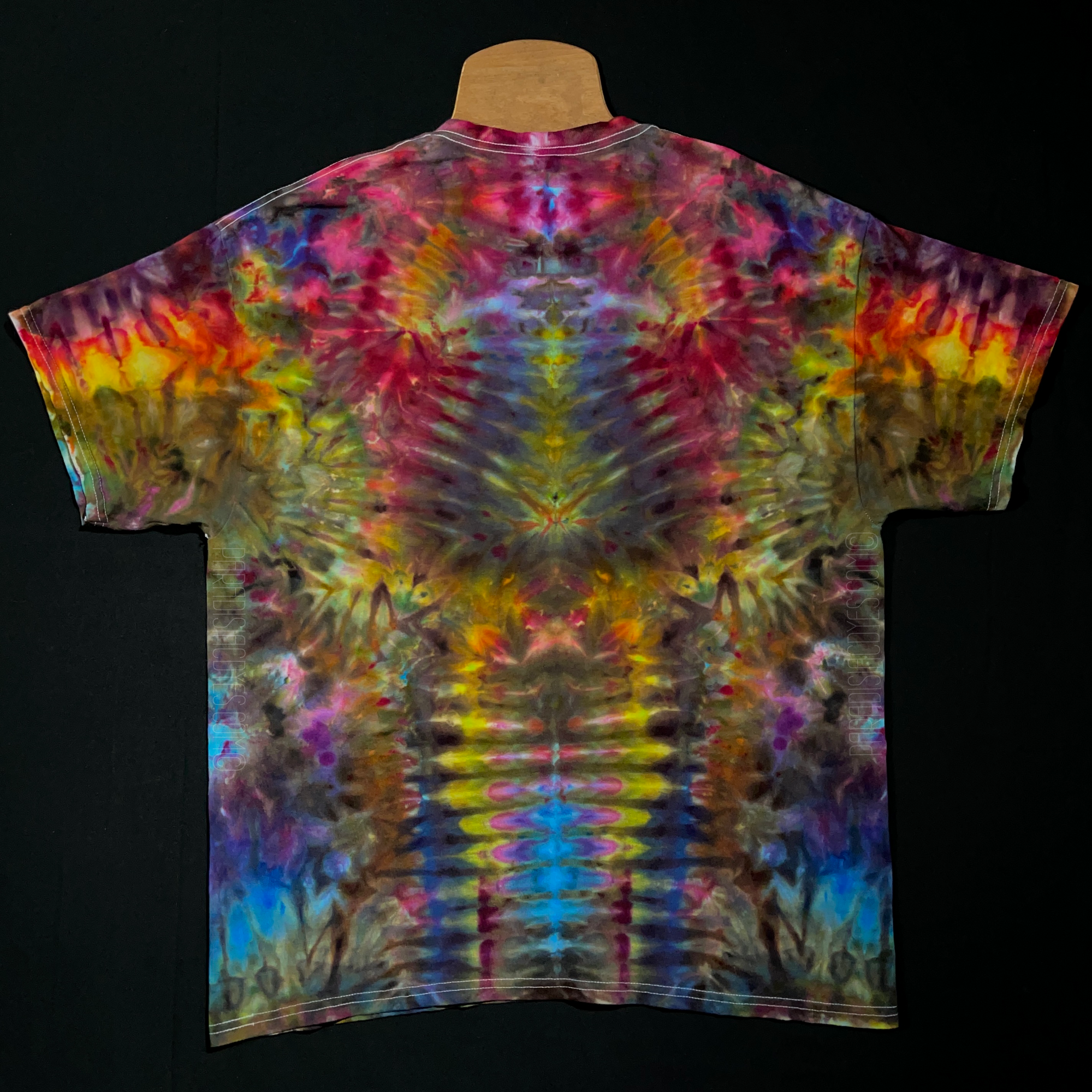 Front side of an abstract, symmetrical ice tie-dyed psychedelic mindscape short sleeve shirt design; featuring a cascading gradient of rainbow colors from top to bottom in a totem pole reminiscent pattern