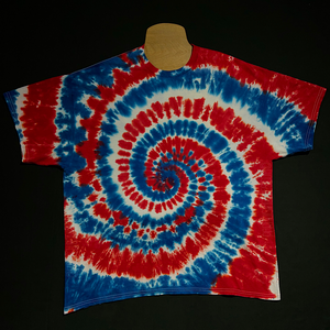 An example of a different 4th of July red, white & blue spiral tie dye short sleeve shirt; laid flat on a solid black background