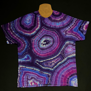 Front side of a hand-dyed, one of a kind agate geode inspired tie dye design featuring an array of purple shades with a distinctly different pattern on each side; laid flat on a solid black background 