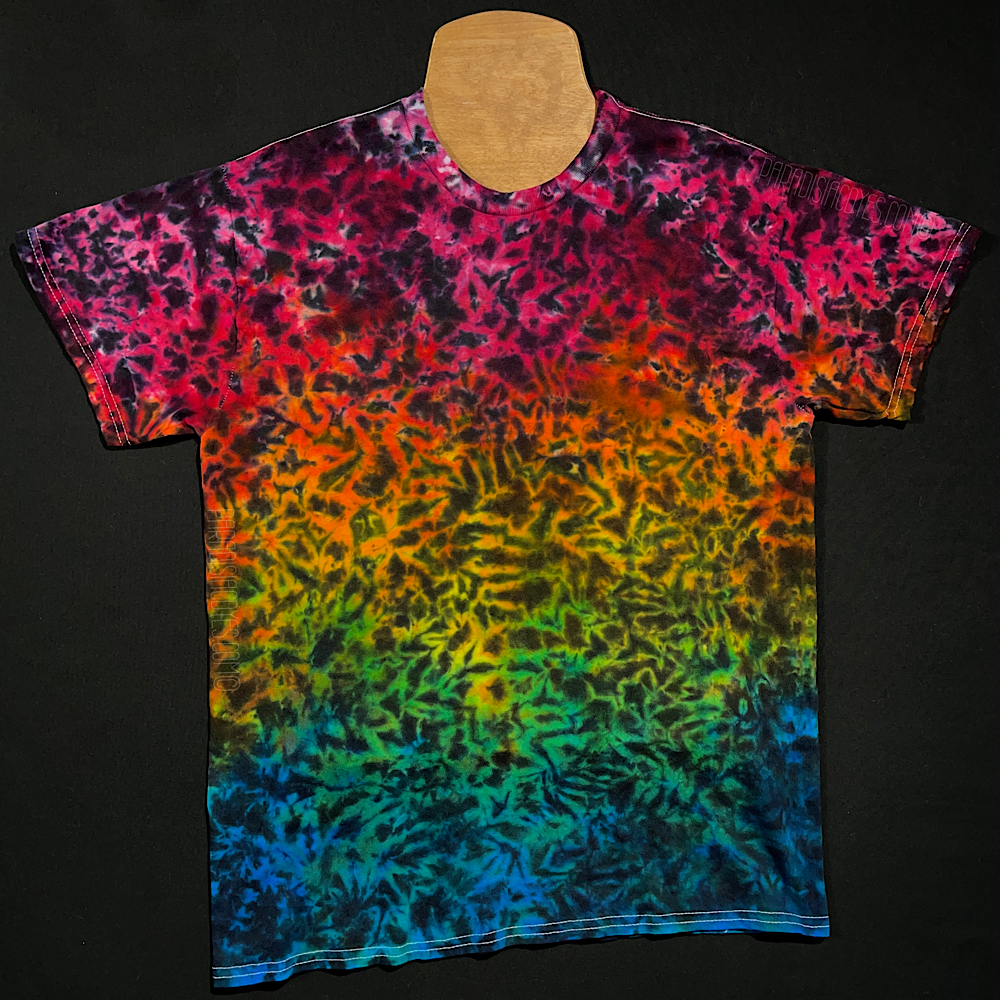An example of a finished Midnight Marbled Rainbow Ice Dye T-Shirt; a rainbow gradient featuring: pink, orange, yellow, green & blue,with black splatter detailing