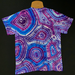 Back side of a purple amethyst quartz geode pattern short sleeve tie dye shirt; laid flat on a solid black background 
