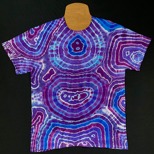 Front side of a handmade-to-order purple amethyst quartz geode pattern tie dye short sleeve tee; laid flat on a solid black background 