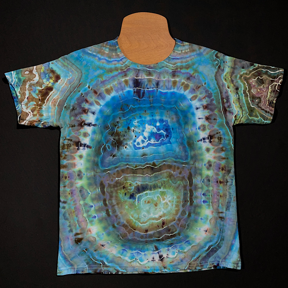 Back side of a youth size large short sleeve shirt featuring a one of a kind giant geode design with mostly blues and hints of light, sandy browns and gray shades