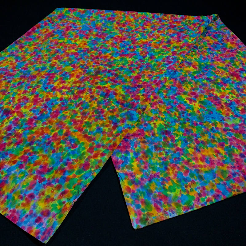 vibrant rainbow splatter pattern tie dye body pillow pillowcase laid flat, folded in half on a solid black background