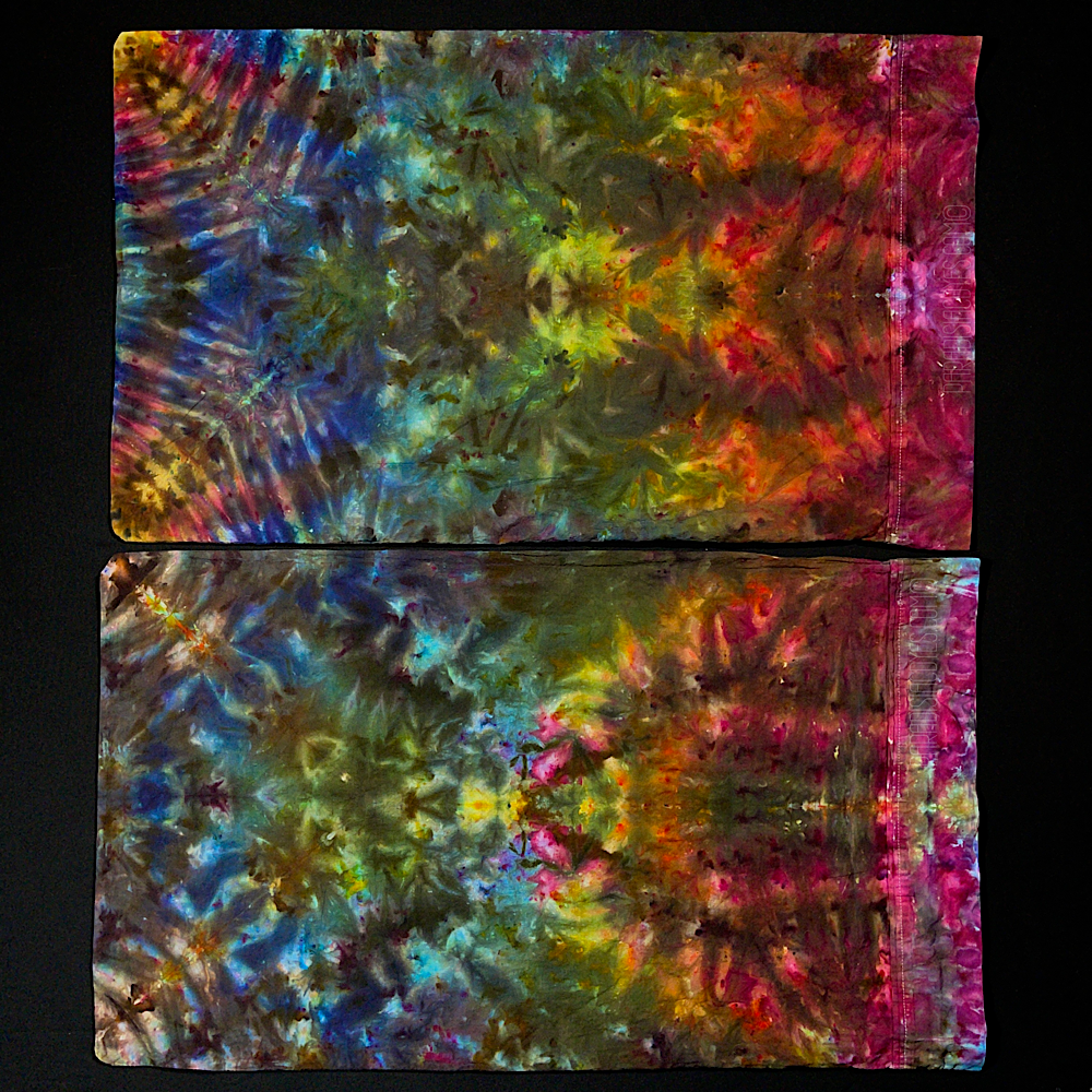 Another angle showing the two standard size pillowcases included in this hand-dyed, one of a kind set that features a symmetrical, psychedelic rainbow gradient design