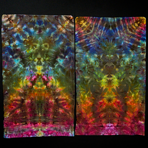 A set of two standard size rainbow gradient psychedelic Mindscape ice dyed pillowcases laid flat, side by side, on a black background