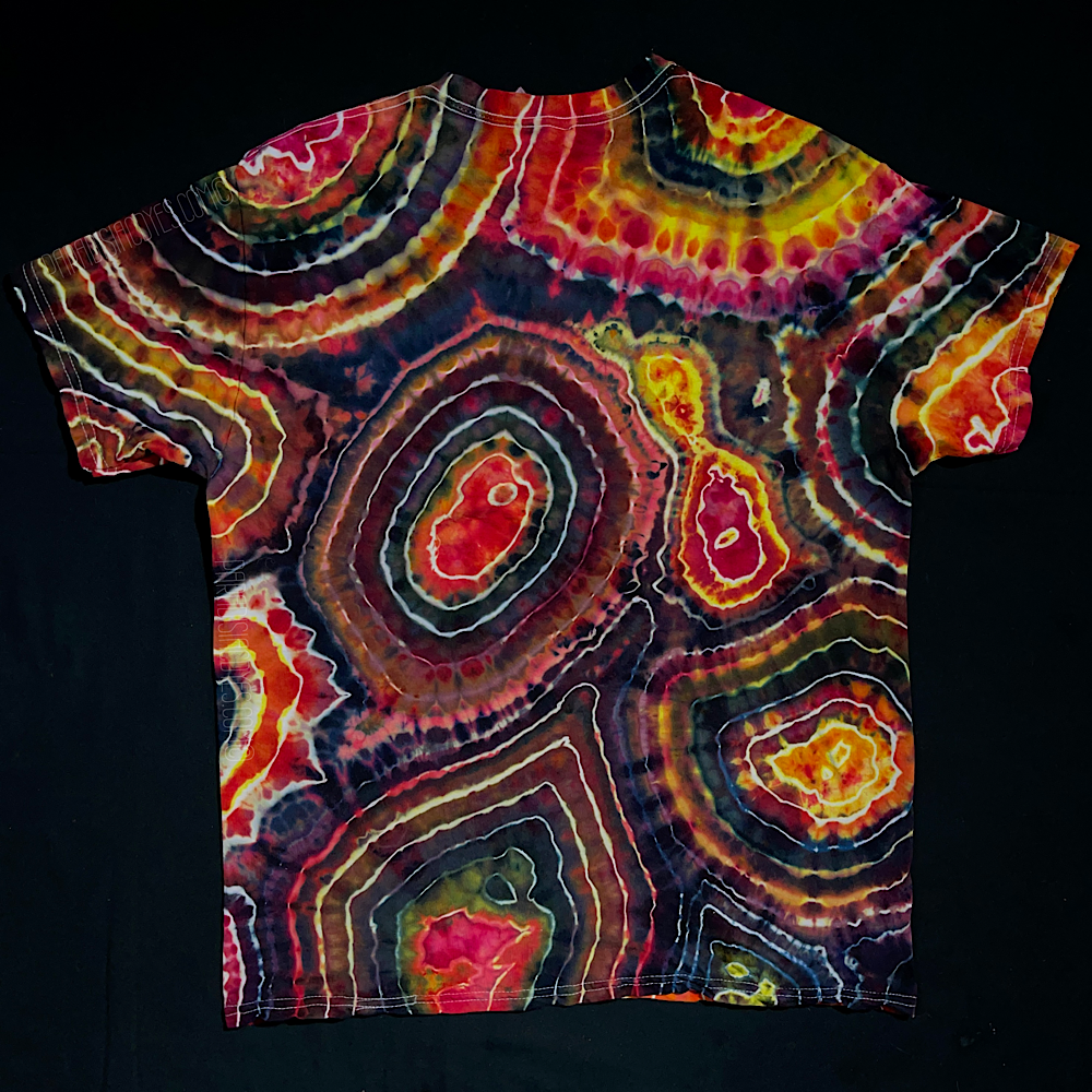 Front side of a short sleeve, crewneck style t-shirt featuring an agate geode reminiscent pattern with shades of pink, yellow & black