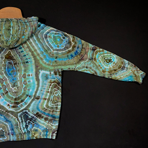 Back side of the right arm sleeve of the earthy, blue agate geode tie dye zip-up hoodie, fully extended to showcase the entirety of the distinctly unique, one of a kind back side of the sleeve design