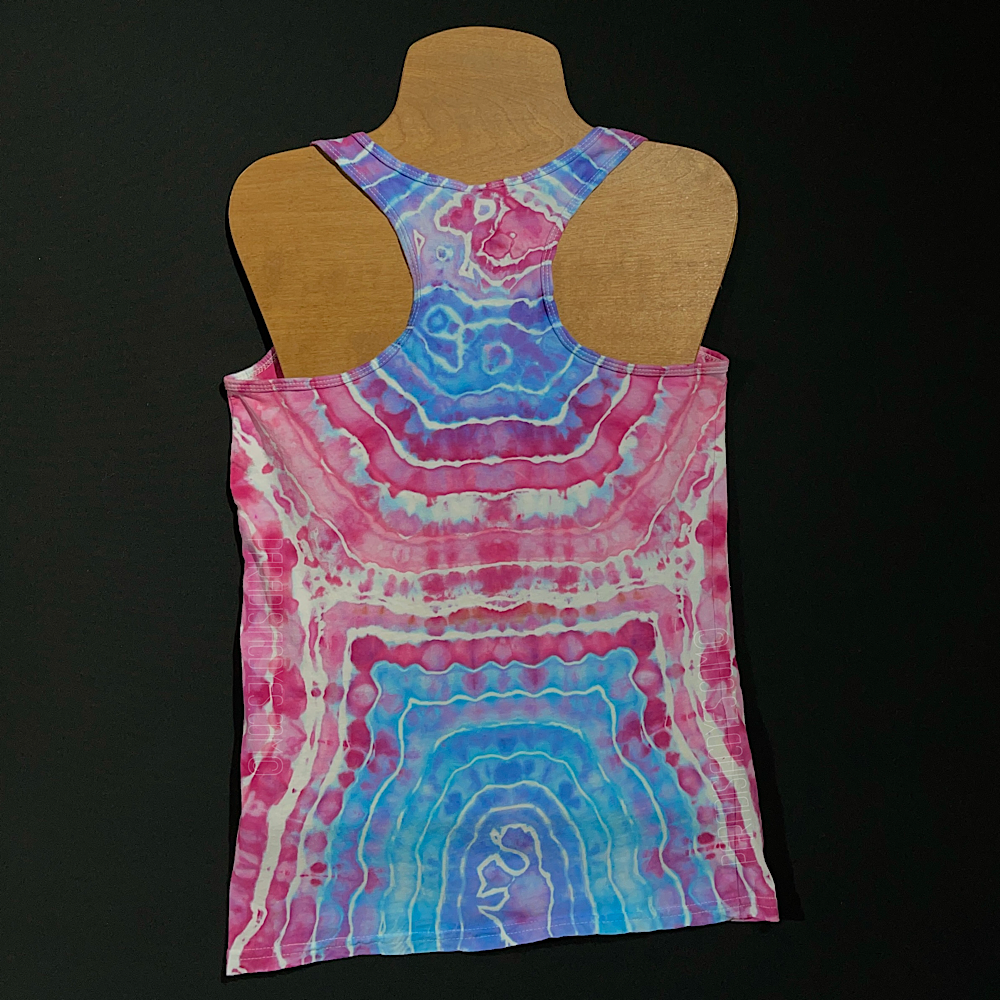 Front side of a ladies size small racerback style tank featuring a geode ice dyed design, with a giant, single geode on the front side with an ocean blue center, transitioning to pink as the bands expand outward